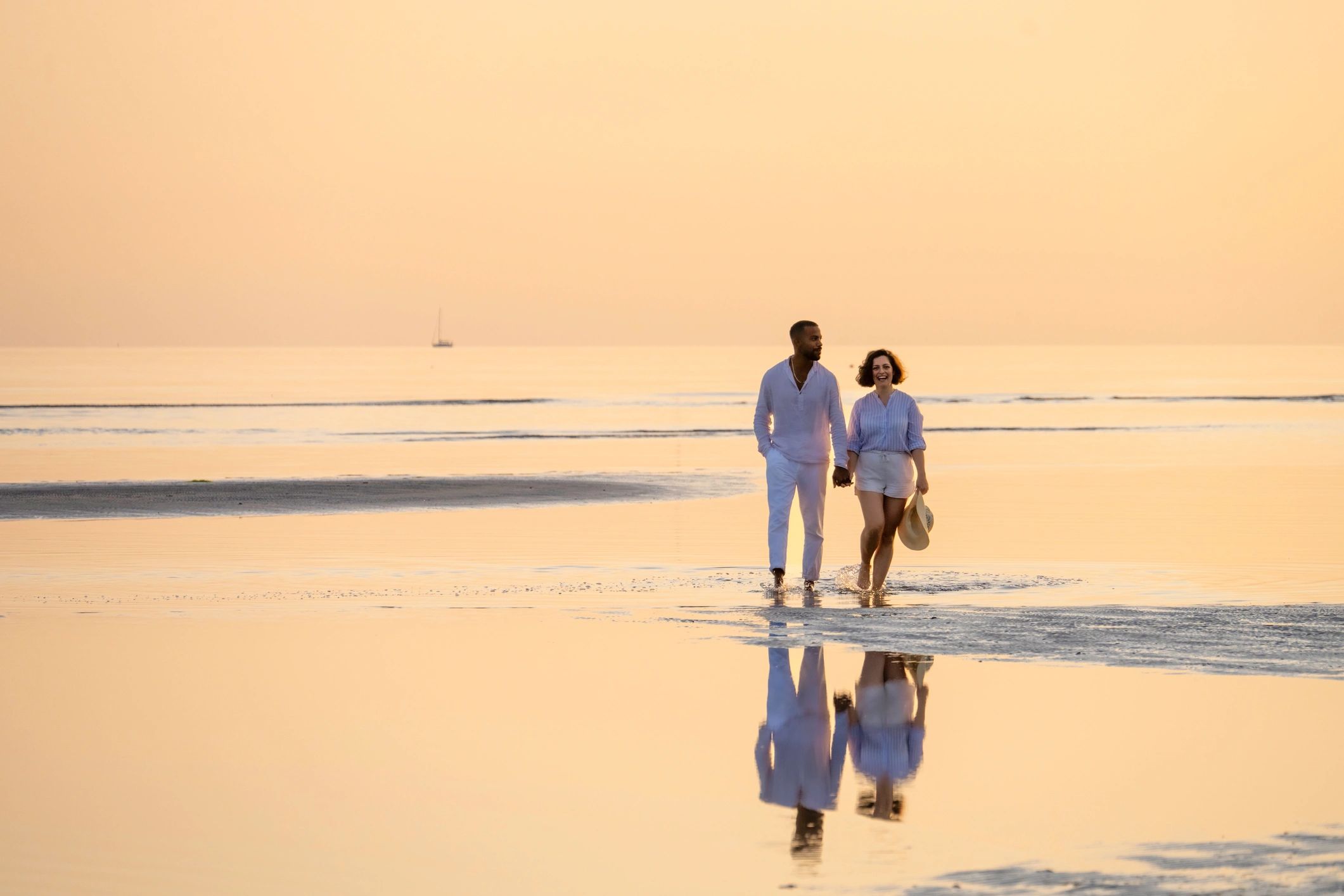 Couple walking along the coastline at sunset